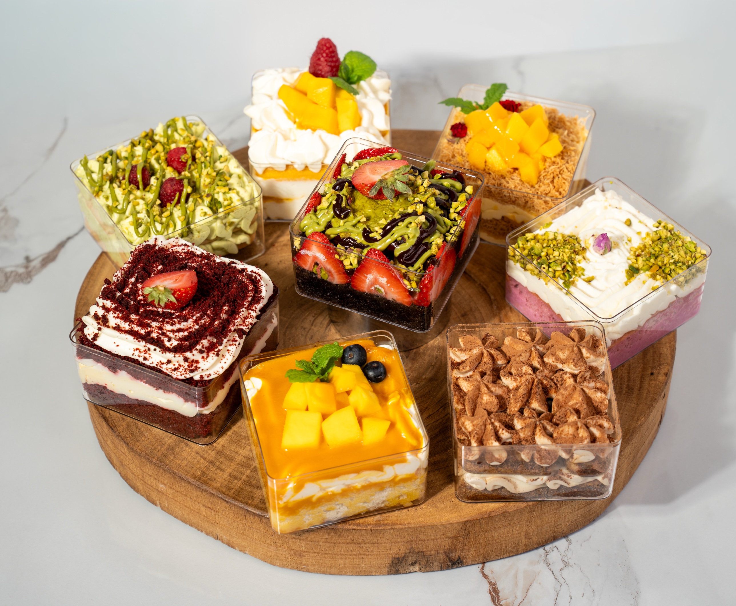 An assortment of Tia Bakery dessert cups on a wooden board