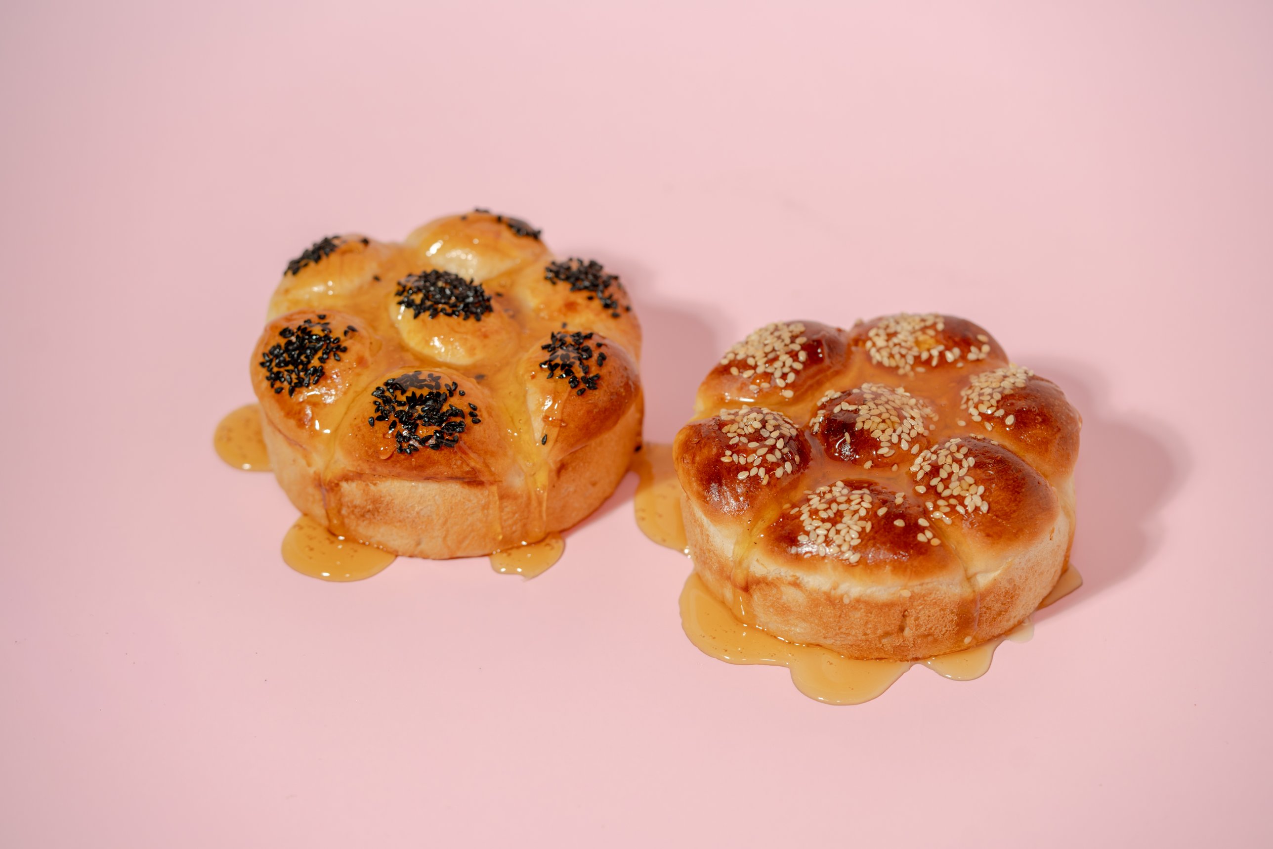 Two honeycomb buns, one with nigella seeds and one with sesame, glazed with honey
